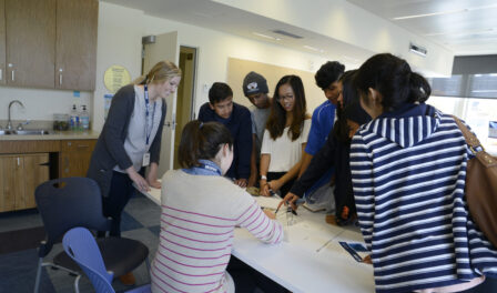 Students around a white table discussing field trip content at MOHAI in downtown Seattle, WA.