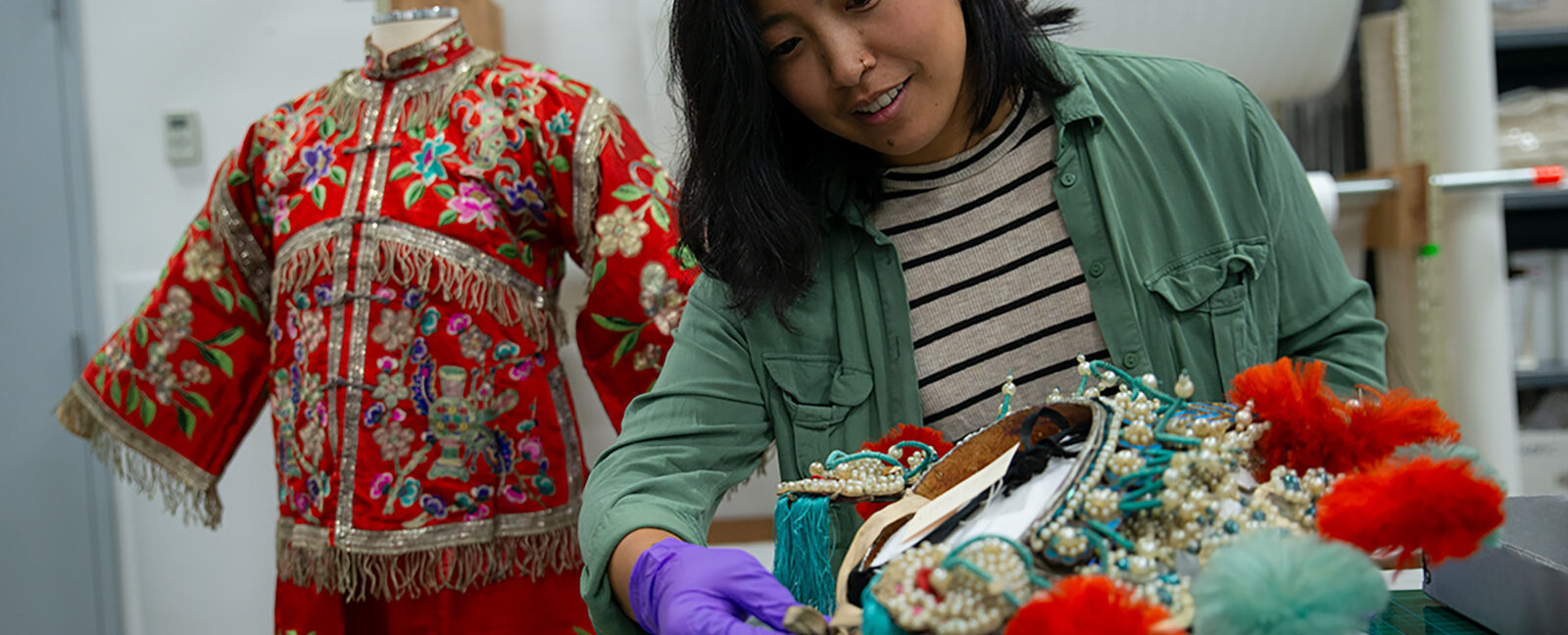 2023 Curator's Fellow Linda Lee, wearing purple gloves, examines artifacts from MOHAI's collection.