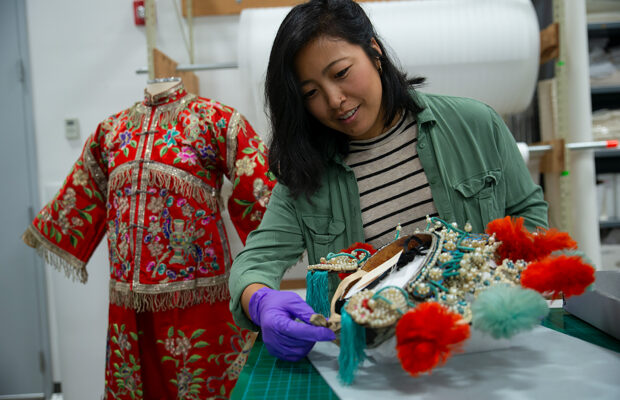 2023 Curator's Fellow Linda Lee, wearing purple gloves, examines artifacts from MOHAI's collection.
