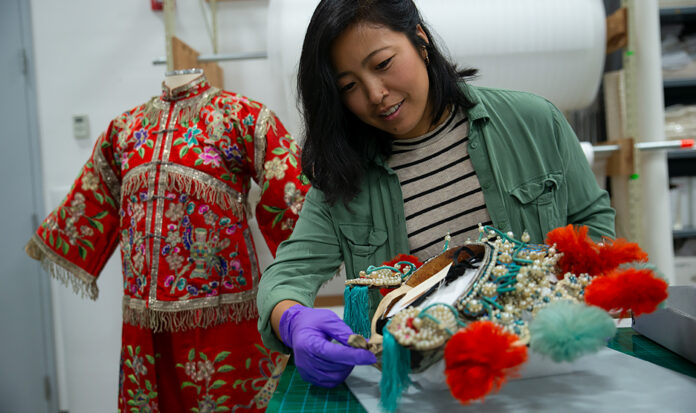 2023 Curator's Fellow Linda Lee, wearing purple gloves, examines artifacts from MOHAI's collection.