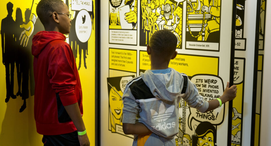 Two young boys read comic panels in the Bezos Center for Innovation at MOHAI.