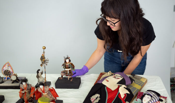 2024 Curator's Fellow Polly Yorioka with Japanese American Boys' and Girls' Day sets from MOHAI's collections.