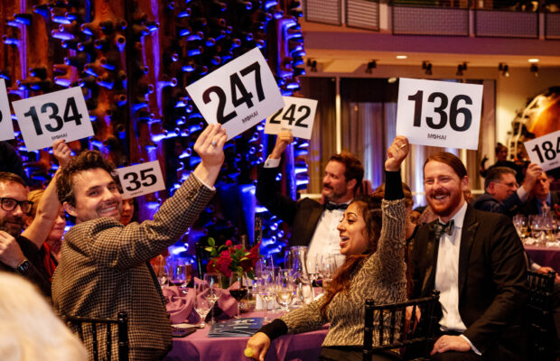 MOHAI Gala attendees sitting at a round table raise their bid numbers.
