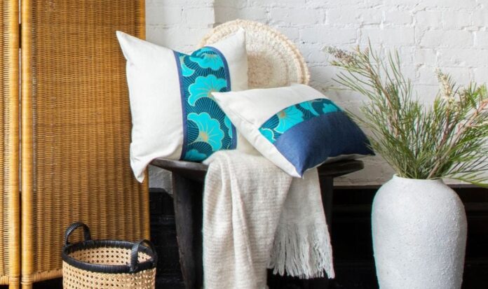 White and blue pillows on a wooden chair adjacent to a wicker privacy screen.