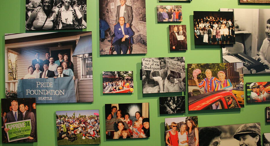 Highlight photos of LGBTQ community centers and leaders that were featured in the Revealing Queer exhibit hung on a green wall.