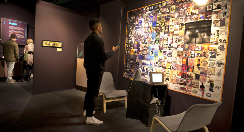 Visitor looking at a wall of Seattle Hip-Hop artists' CD covers.