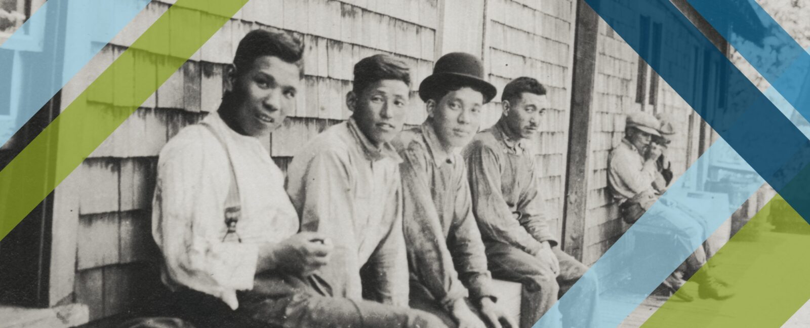 Migrant laborers sitting against side of home covered with cedar shakes.