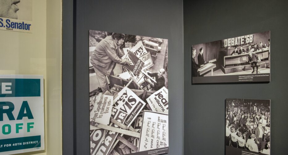 Three photos displayed at exhibit. One shows a man handing out picket signs, one is a 1968 debate, one is a rally.