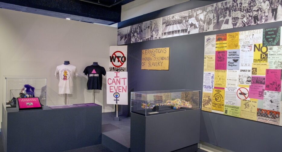 Wide view of Stand Up Seattle exhibit showing various photos, displays, and a painted electric guitar.