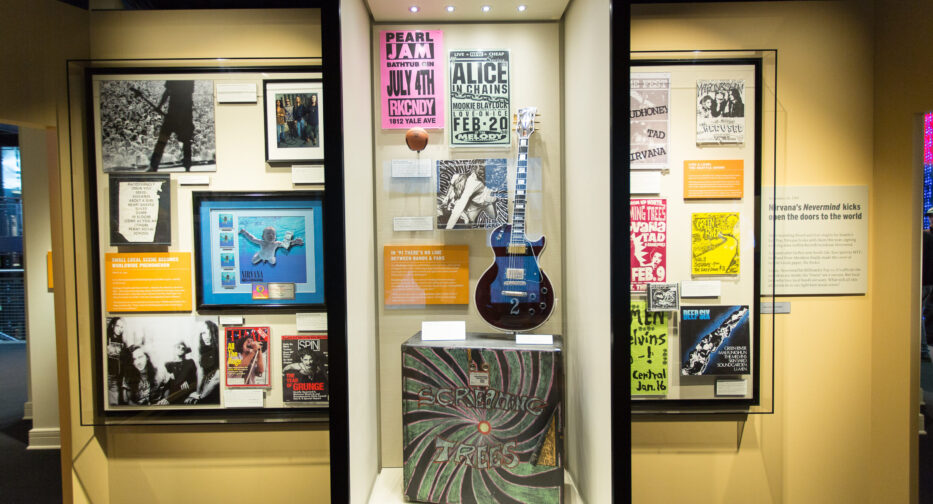 An exhibit at MOHAI showing various artifacts from Seattle grunge era bands including Nirvana, Pearl Jam, Alice in Chains, Screaming Trees, and Mudhoney.