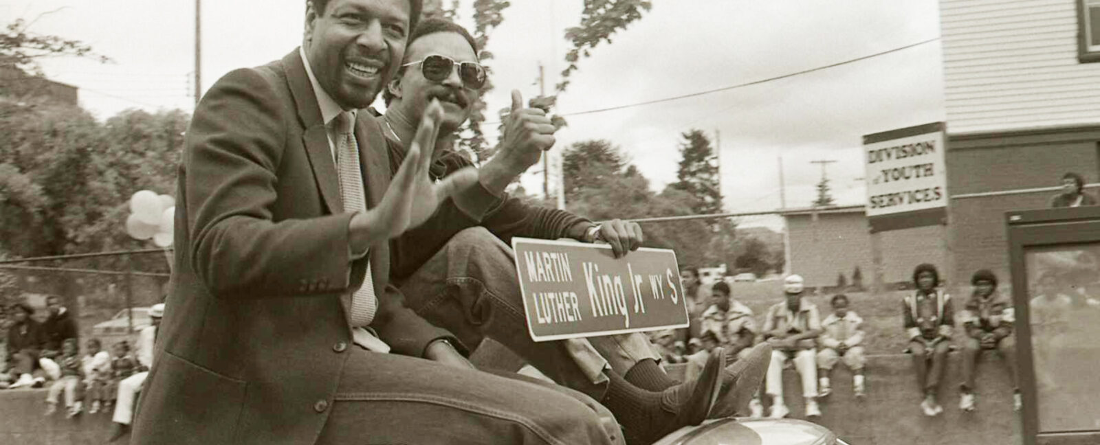 Two individuals seated on the roof of a car