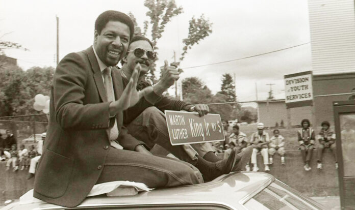 Two individuals seated on the roof of a car