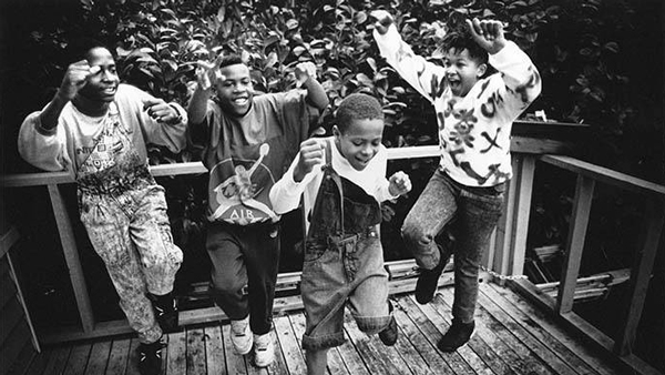 Four children dancing on a wooden deck.