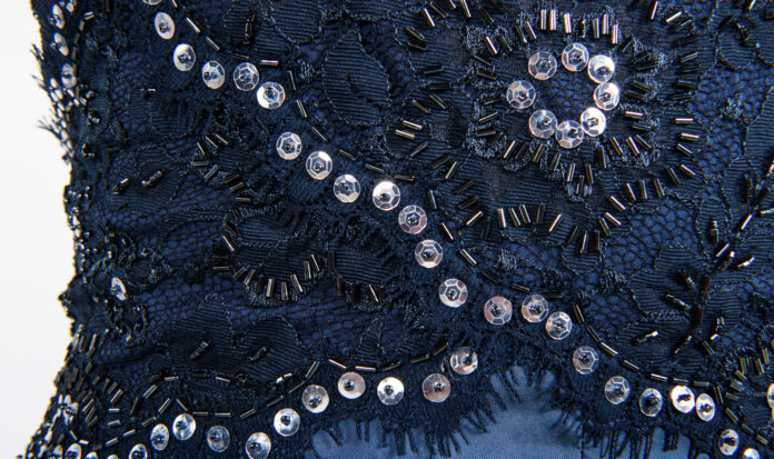 Close up of a blue gown covered in sequins and beads.