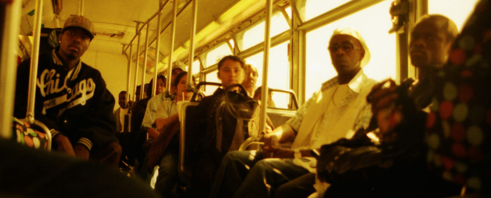 The inside of a bus shows eleven riders. No one is smiling.