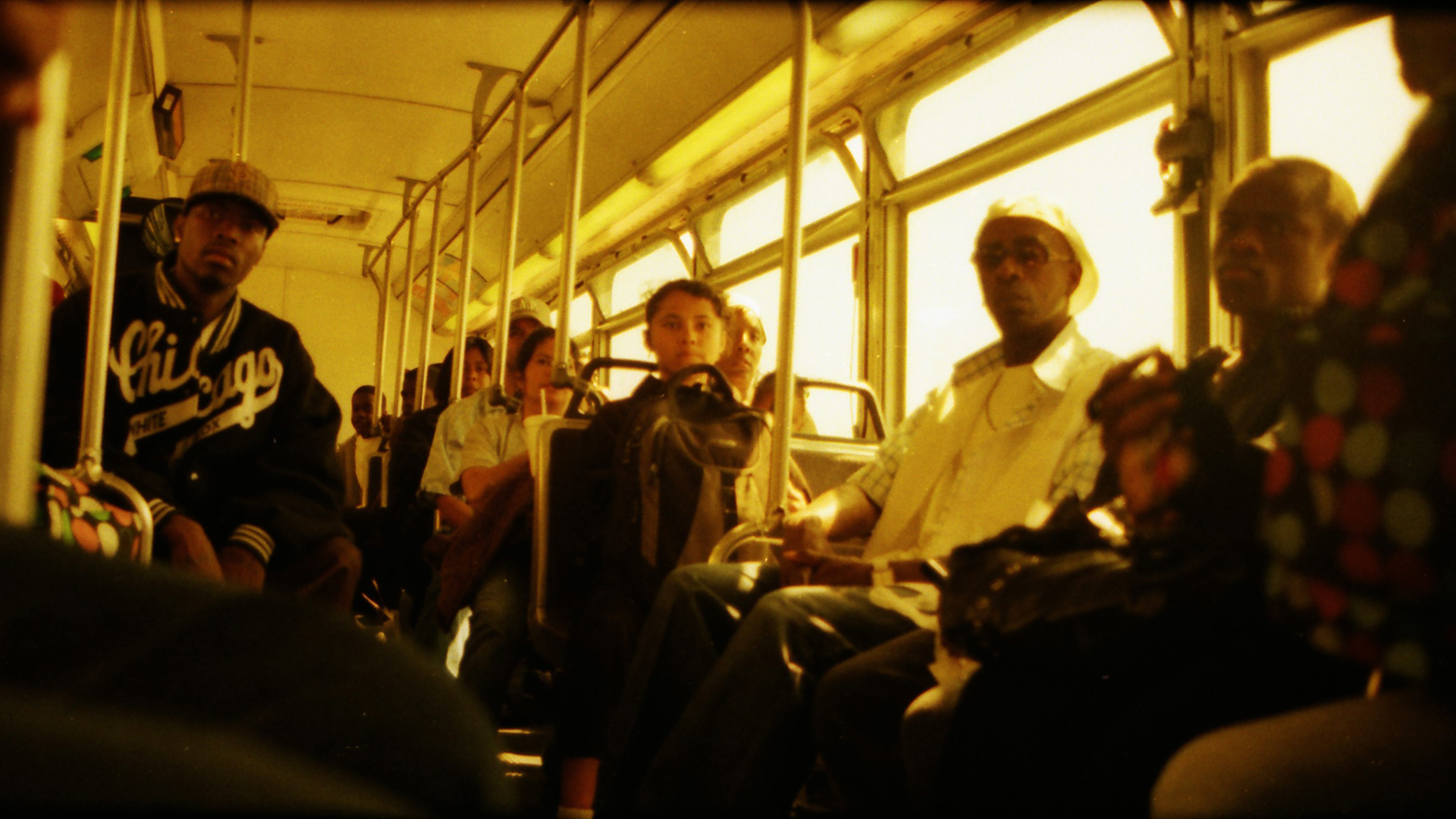 The inside of a bus shows eleven riders. No one is smiling.