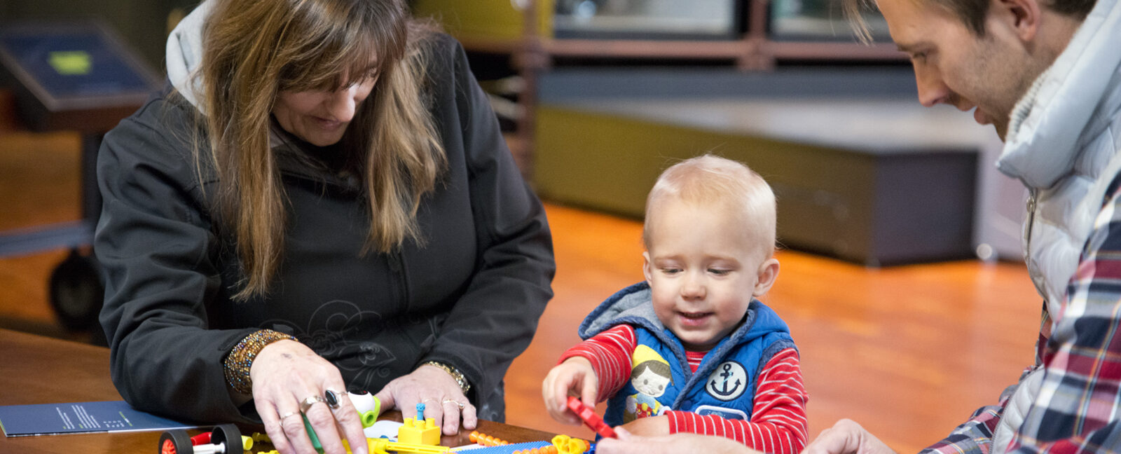 Child and parents playing with building toys.