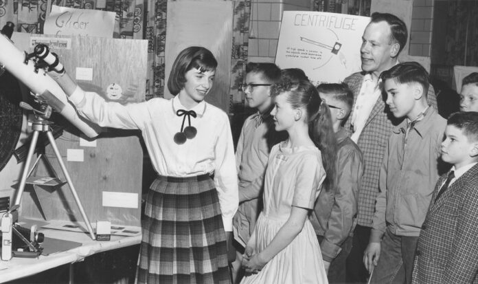 Thirteen-year-old Peggy Dibble shows her exhibit on "The Making and Use of a Telescope" at the 1961 King County Science Fair.