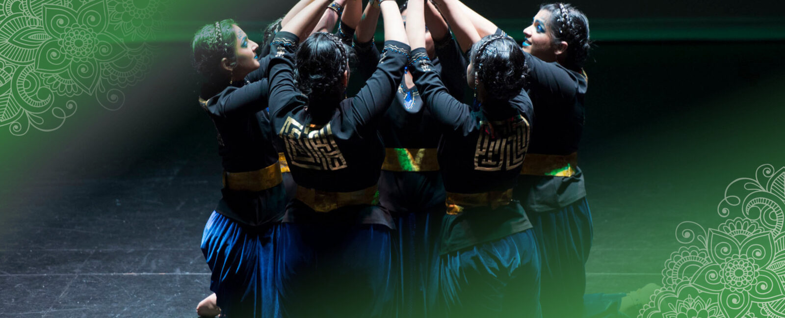 A group of individuals on their knees in a circle with arms raised and meeting above.