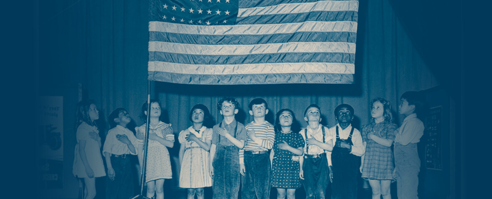 Children with left hands over hearts gazing at US flag.