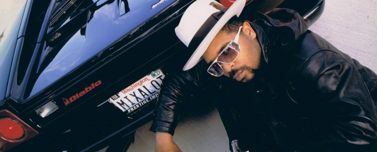 Sir Mix-a-Lot crouching behind a Lamborghini Diablo with a "MIXALOT" Washington license plate.