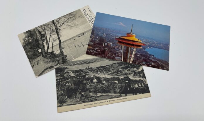 Three postcards showing Seattle through history placed in a neat pile. You can see the Space Needle