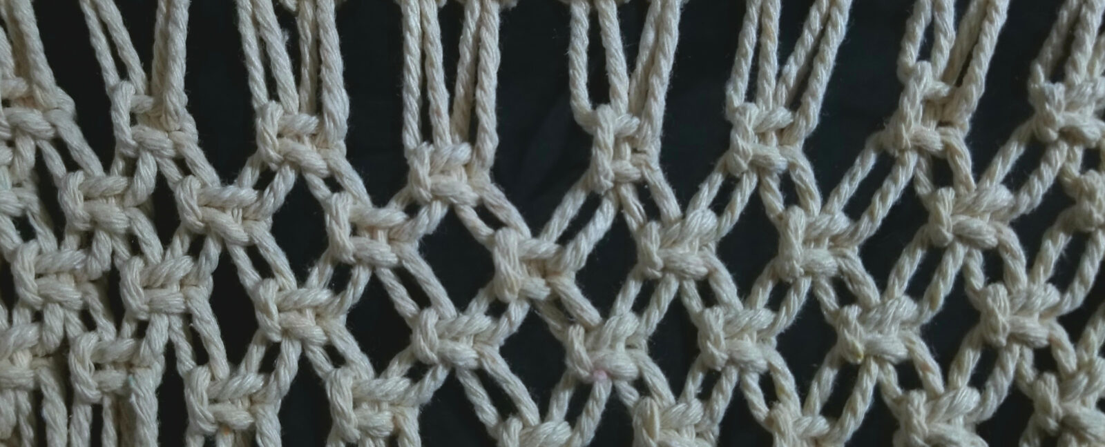 A close up of white yarn being used in macrame.