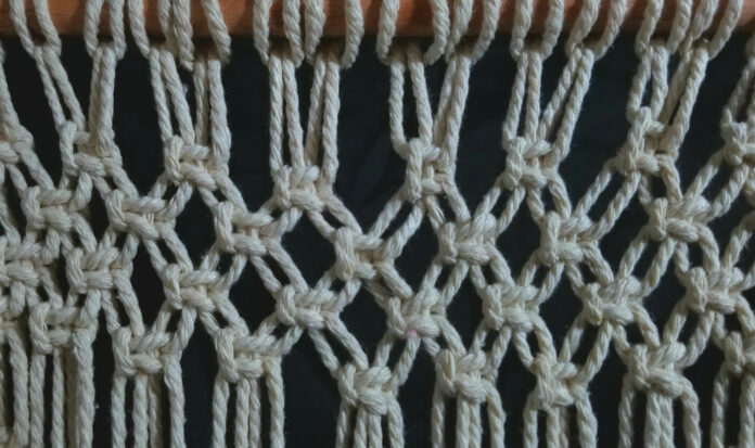 A close up of white yarn being used in macrame.