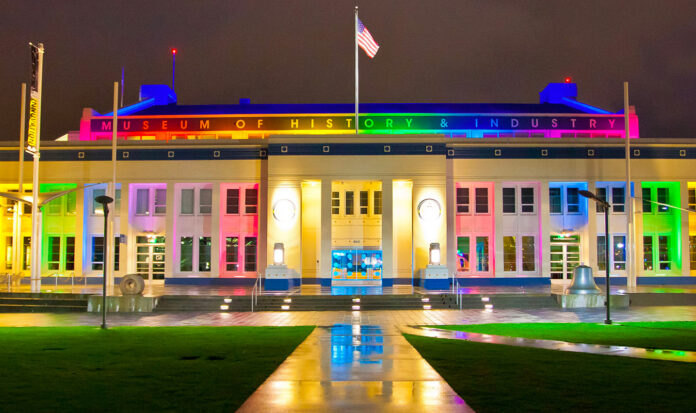 Exterior photo of MOHAI at night lit up in rainbow colors.
