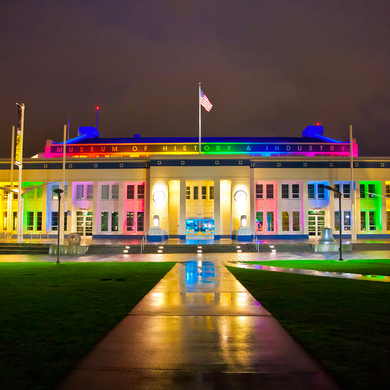 Exterior photo of MOHAI at night lit up in rainbow colors.