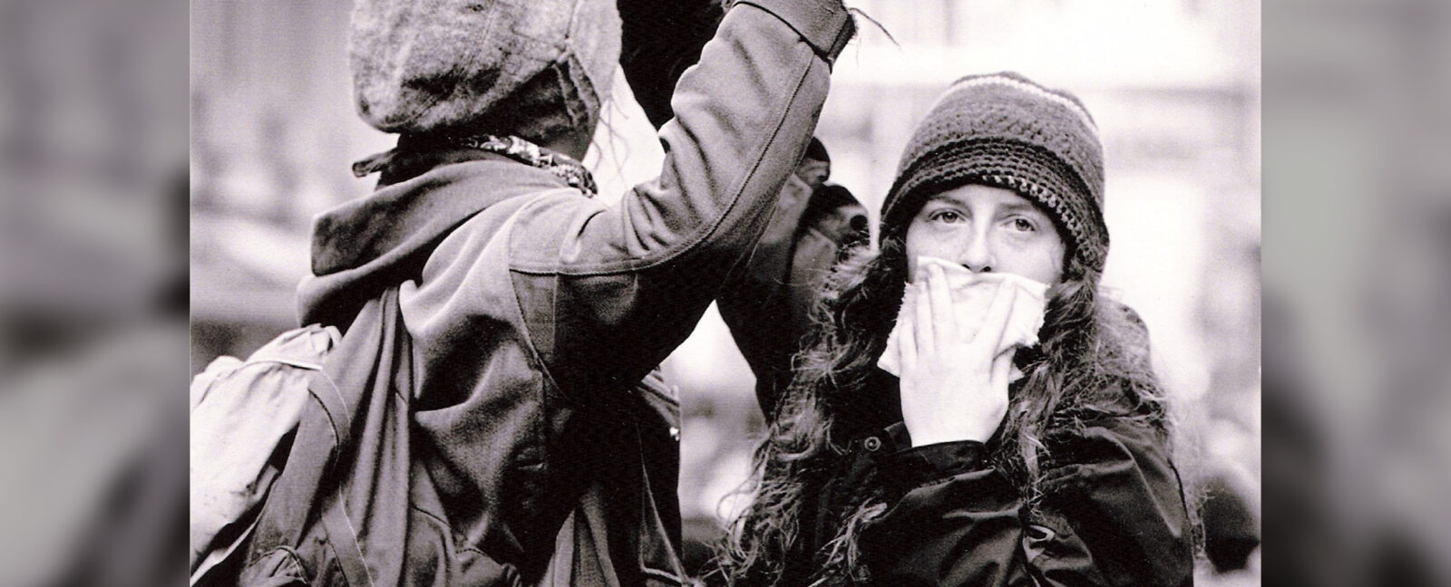 Two protesters. One looking at camera while covering her mouth.