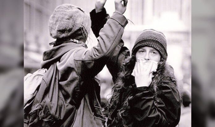 Two protesters. One looking at camera while covering her mouth.
