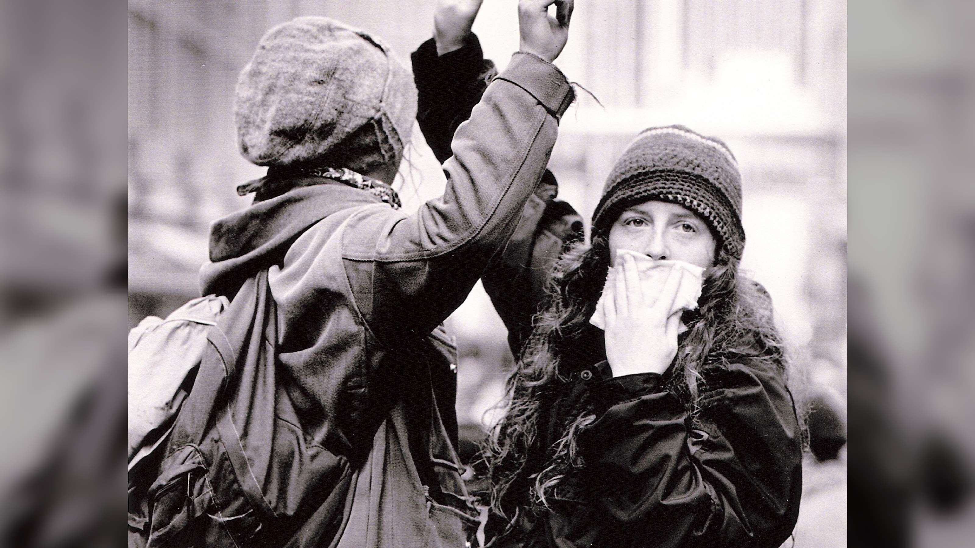 Two protesters. One looking at camera while covering her mouth.