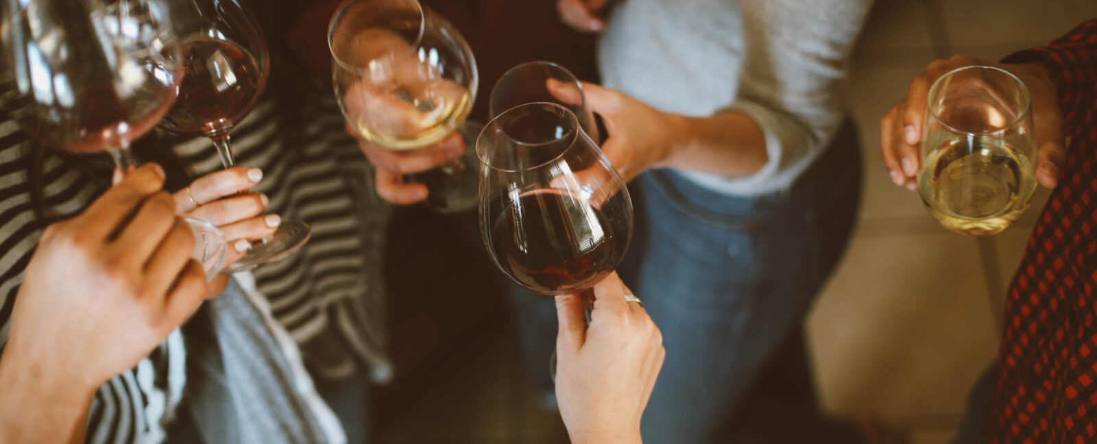 A top-down view of six people holding glasses of red and white wine.