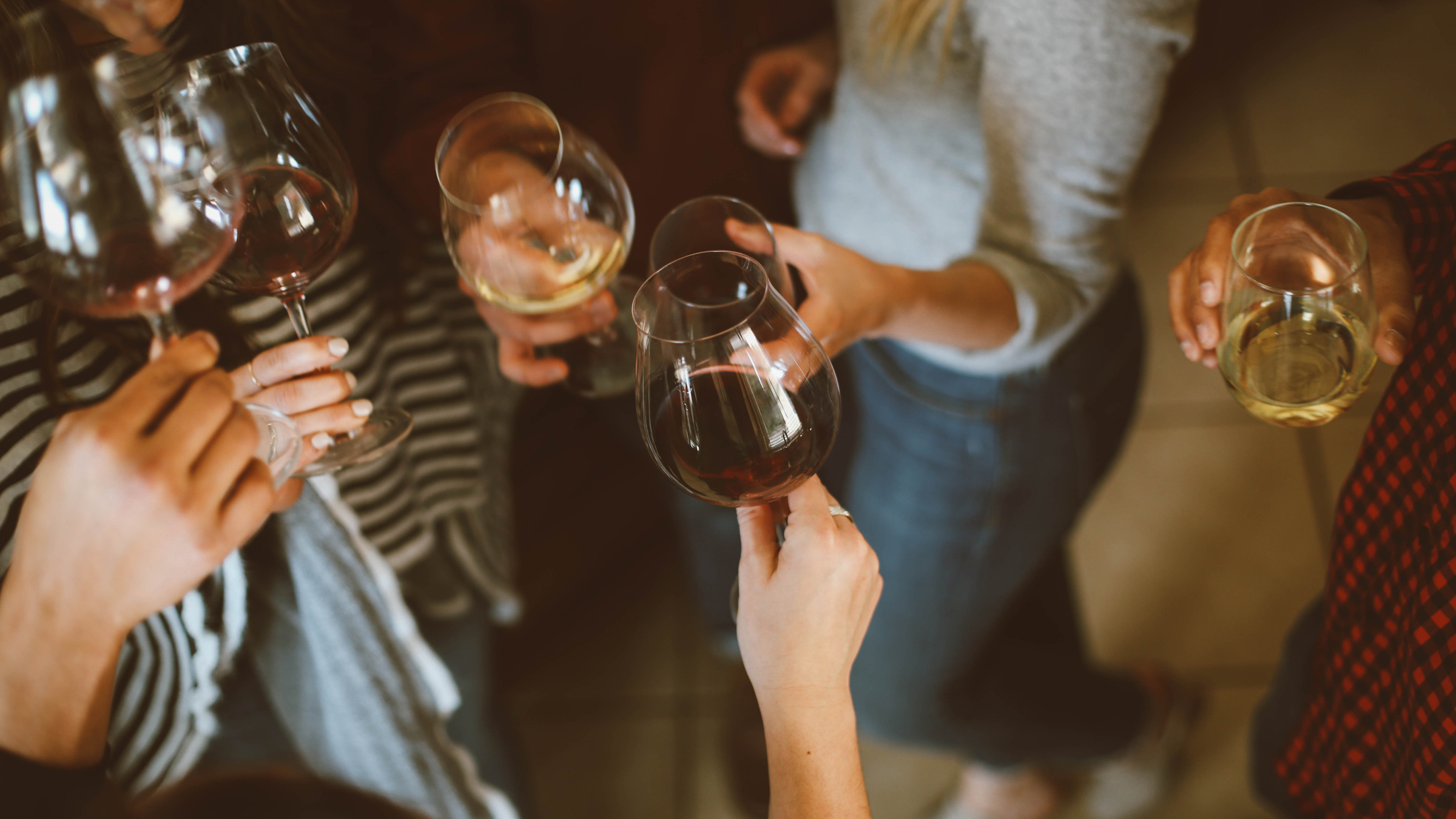 A top-down view of six people holding glasses of red and white wine.