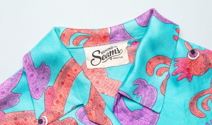Teal shirt with orange and purple design. Tag reads "Behind the Seams