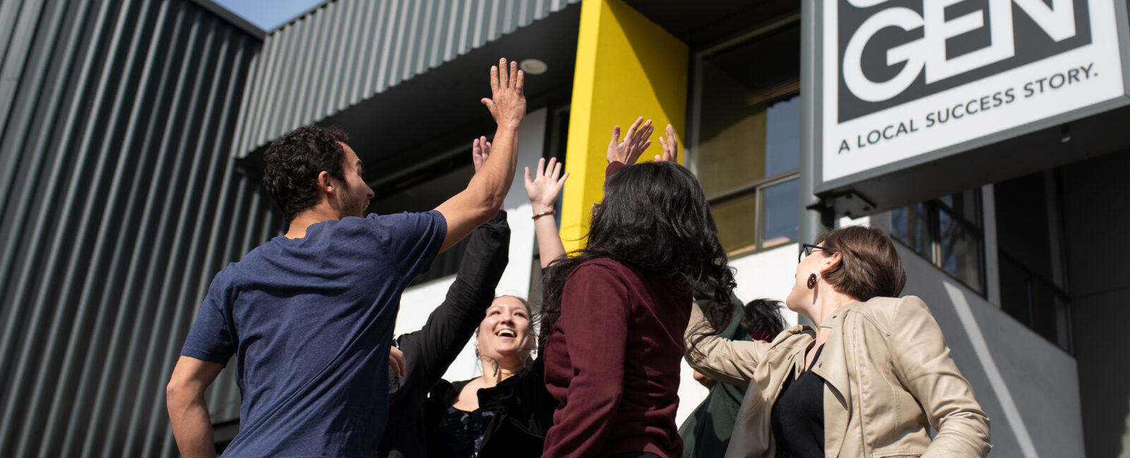 A group of individuals high-five outside of 8th Generation.