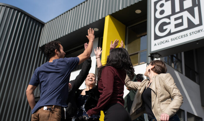 A group of individuals high-five outside of 8th Generation.