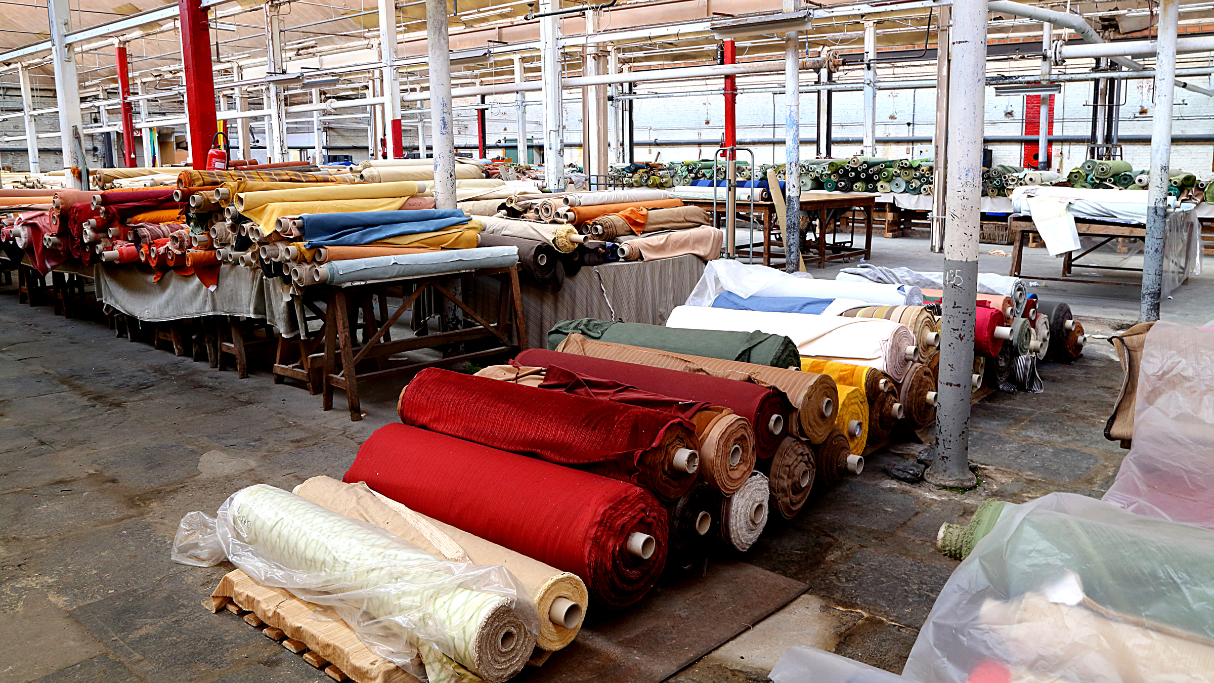 A factory with numerous rolls of fabric neatly stacked on shelves