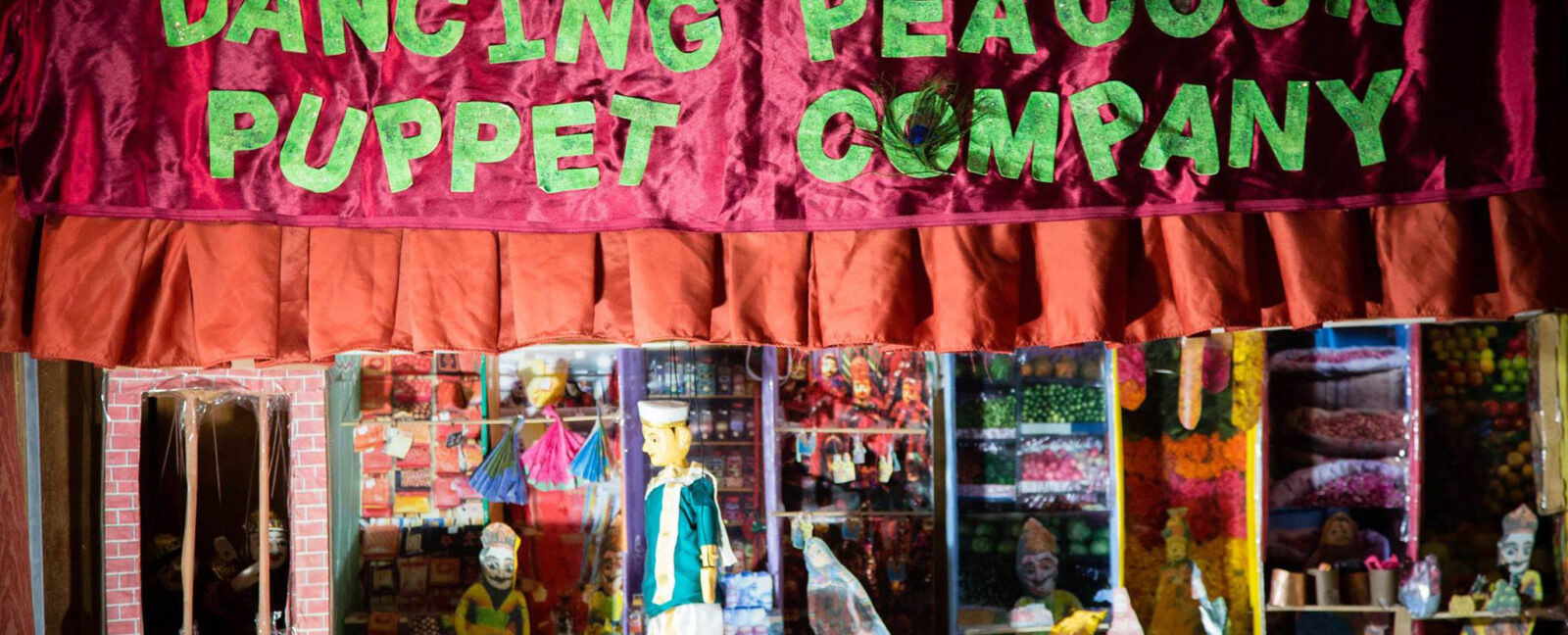 Dancing Peacock Puppet Company banner with puppet and stage below.