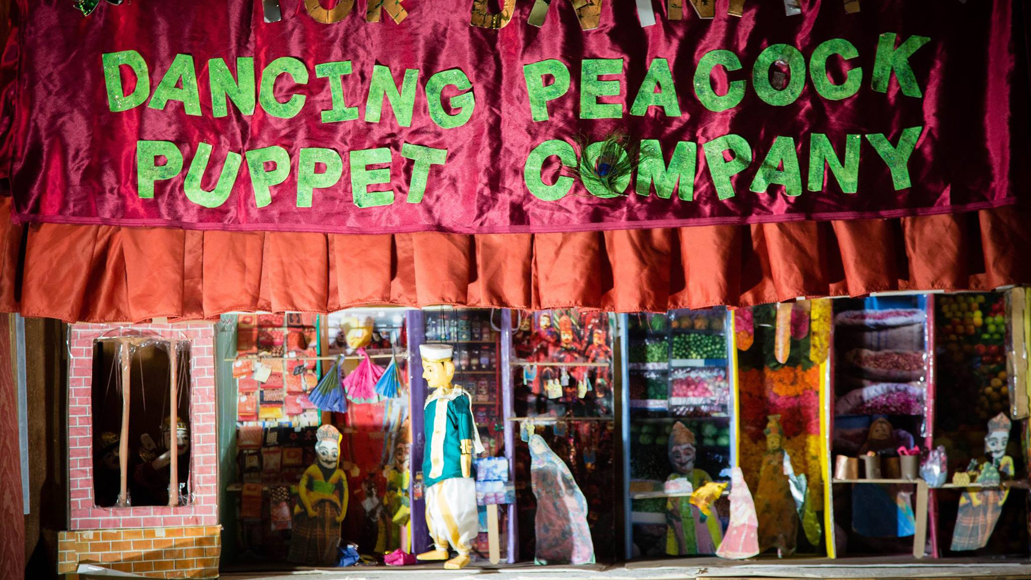 Dancing Peacock Puppet Company banner with puppet and stage below.