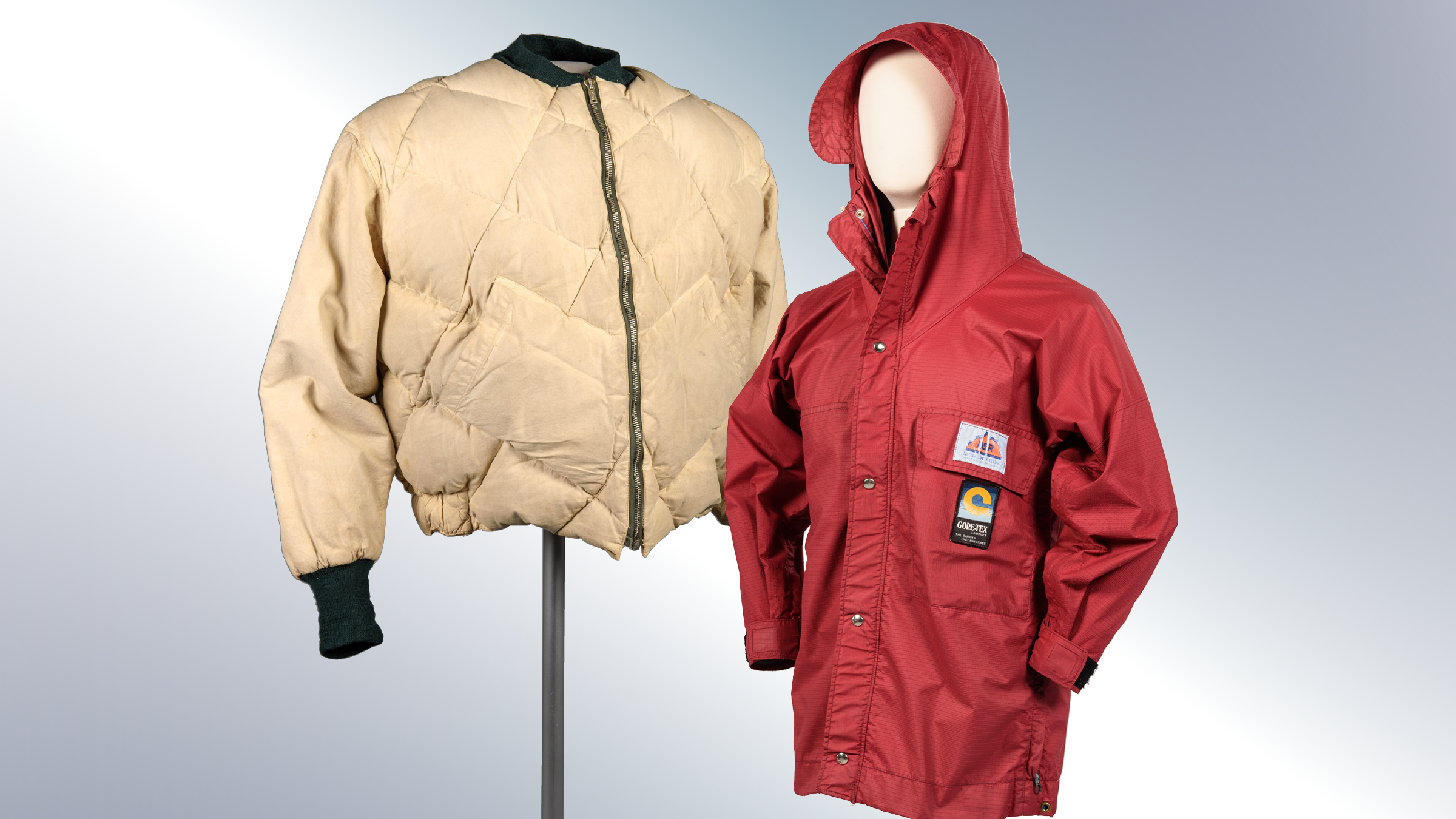 Two coats on display. The left coat is cream colored. The right coat has a hood and is red colored.