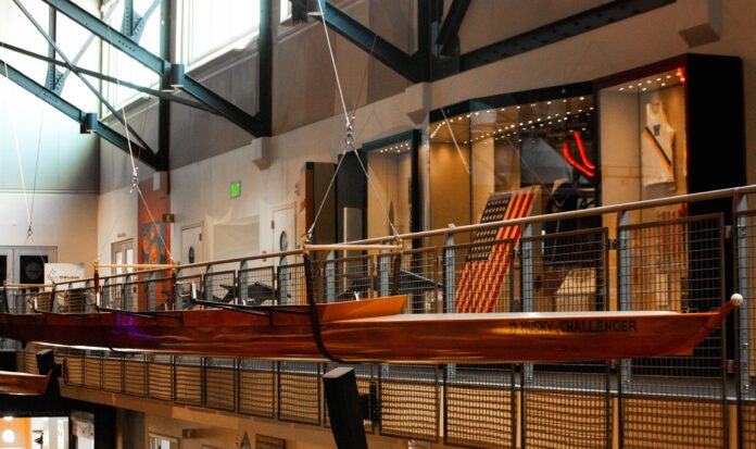 The Husky Challenger racing shell hanging in the Grand Atrium at MOHAI. The United States flag is visible in the background.