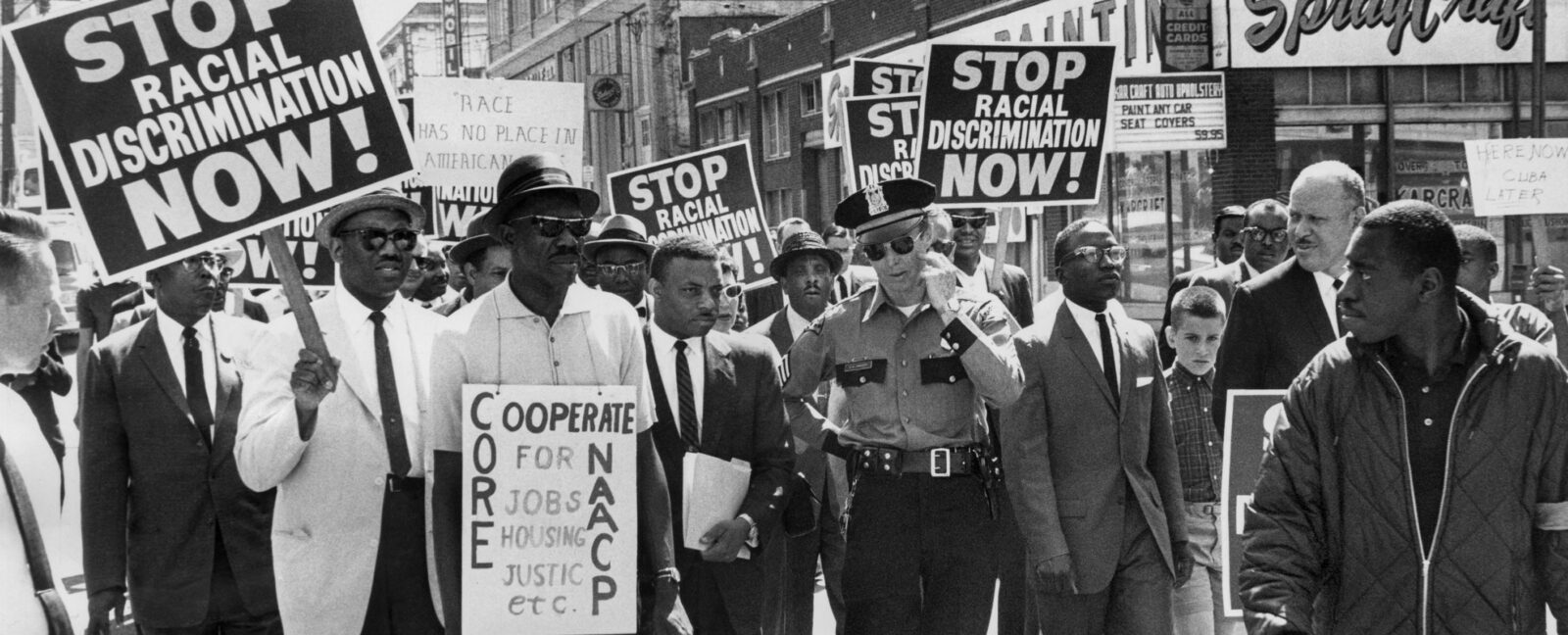 Black protestors peacefully marching with white police officer.