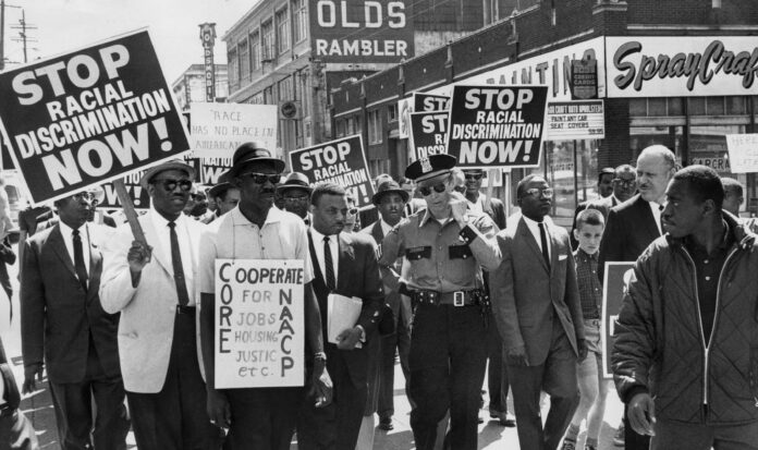 Black protestors peacefully marching with white police officer.