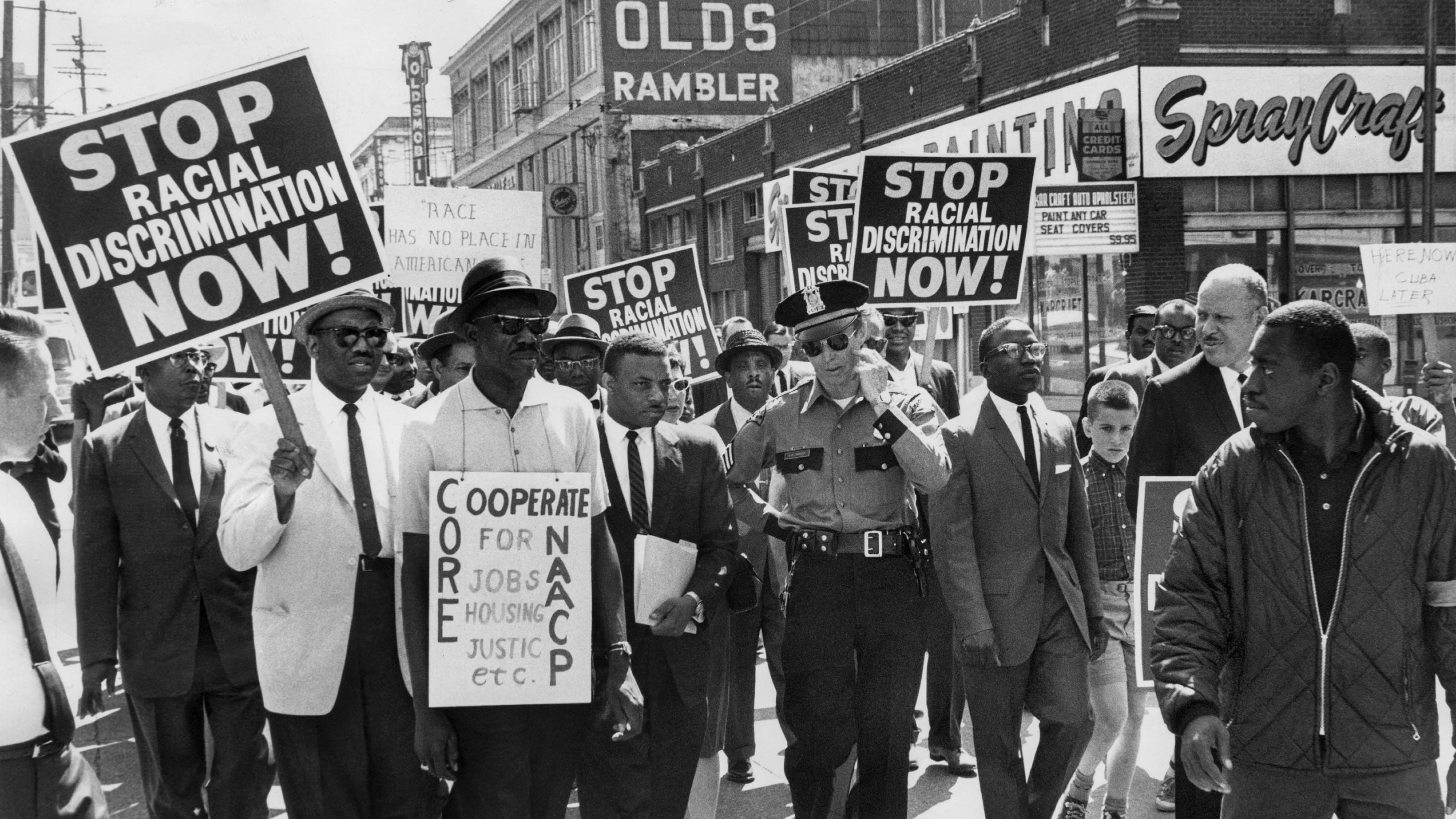 Black protestors peacefully marching with white police officer.