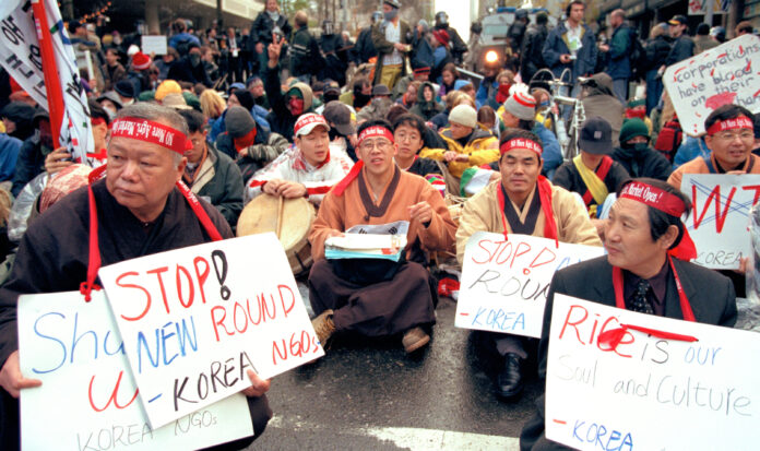 Korean farmers sit in the street with protest signs at WTO protest, Seattle, November 30, 1999.