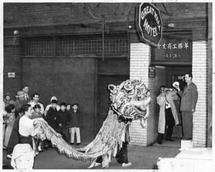 Black and white photograph of a group of children next to a lion dance costume.