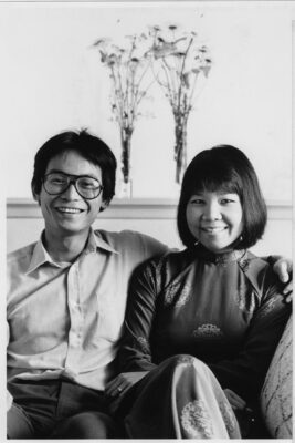 Black and white photograph of Duong Tran and Kimlien Tran sitting together on a couch and smiling.