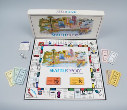 A board game featuring Seattle landmarks like the Space Needle, with colorful cards, dice, and play money.